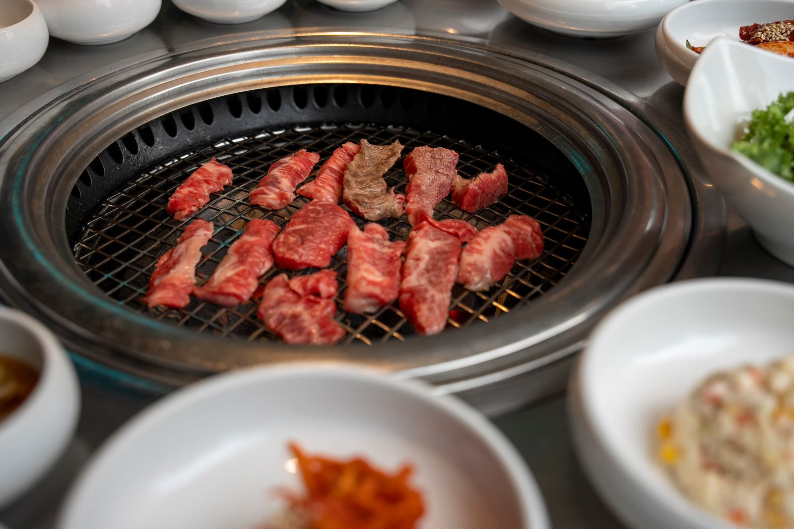 Cuts of beef cooking on a Korean BBQ grill